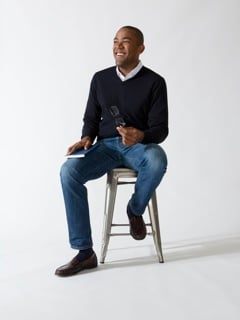 man sitting on stool smiling.
