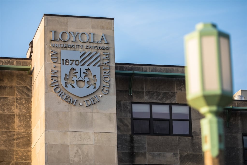 A building on the Lakeshore Campus displays the shield of Loyola University Chicago with the motto: Ad majorem dei gloriam.